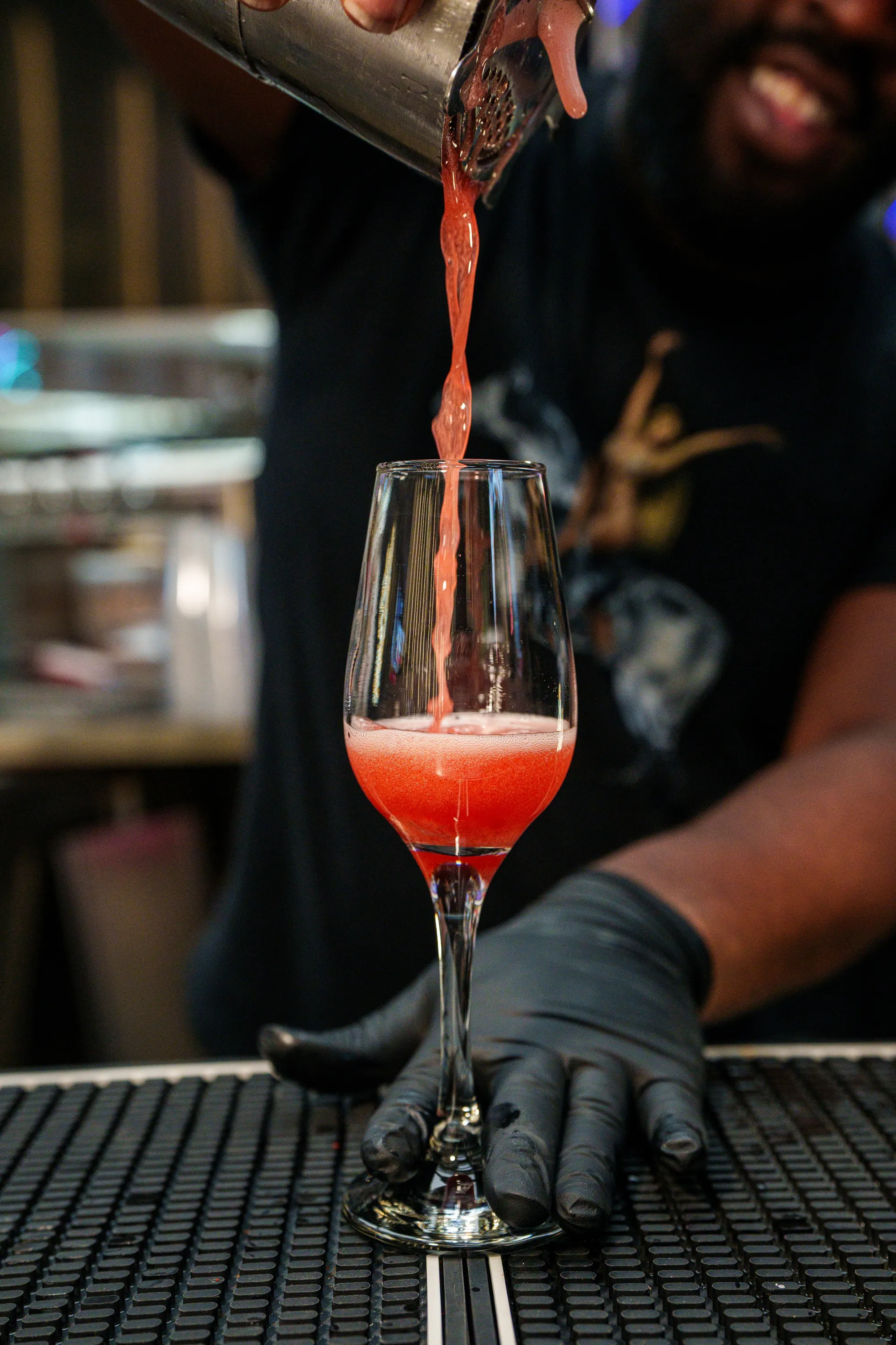 A bartender pouring a red cocktail at Return to Sender