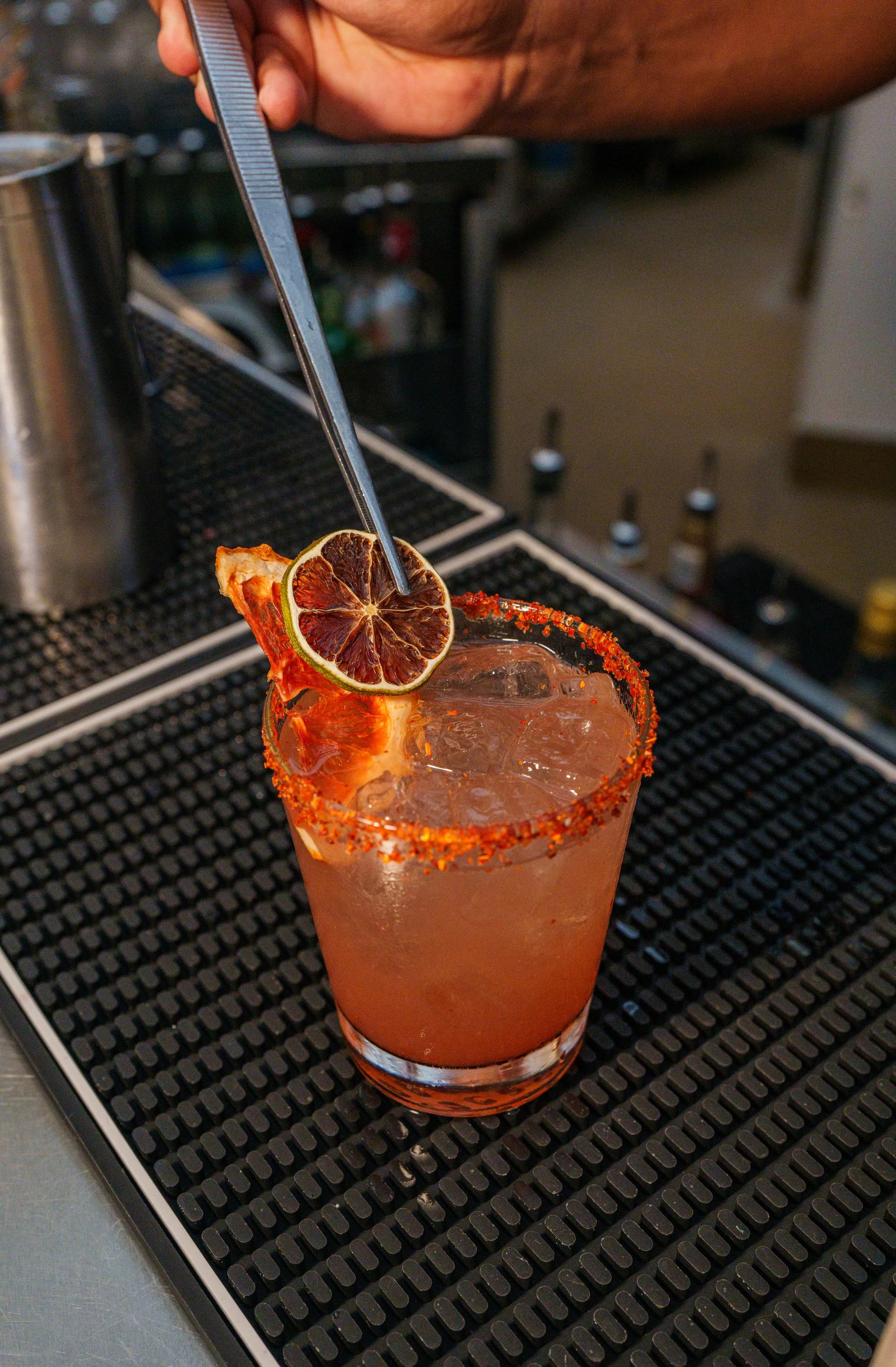 A bartender finishing a cocktail with a dried citrus garnish